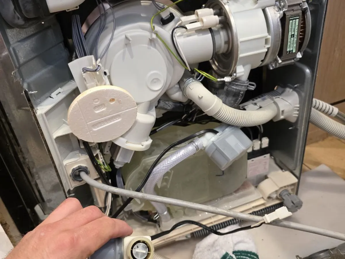 Dishwasher pulled out for repair with the pump and hoses exposed